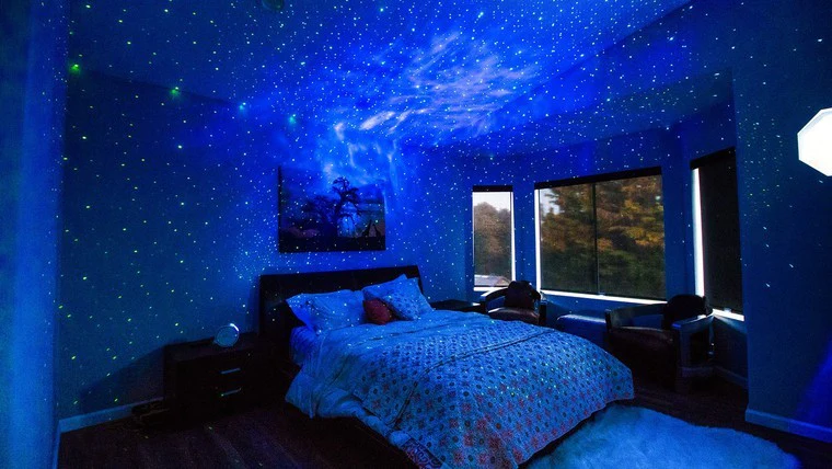 A view of a bedroom with blue galaxy light projector on