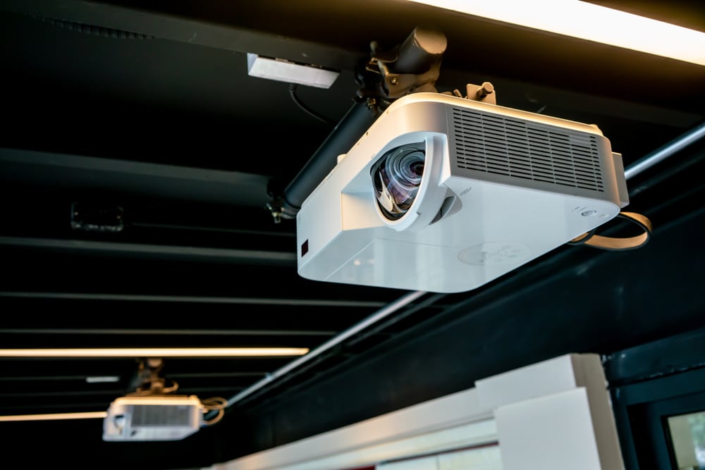 Black Ceiling Hanging White Projector With Metal Tube Against Black