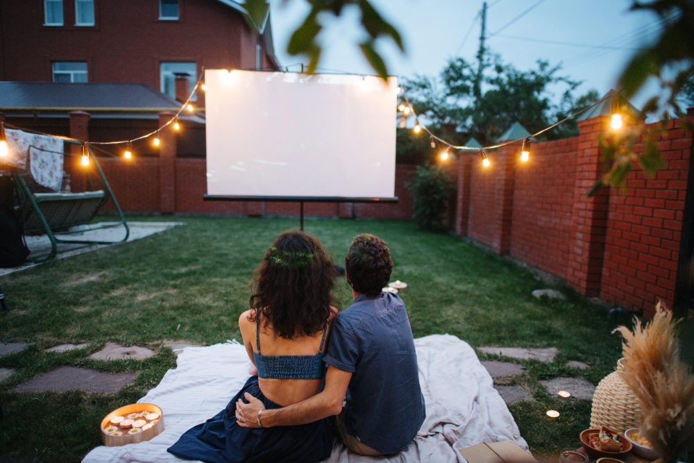 A back view of a couple watching stuff on an outdoor projector