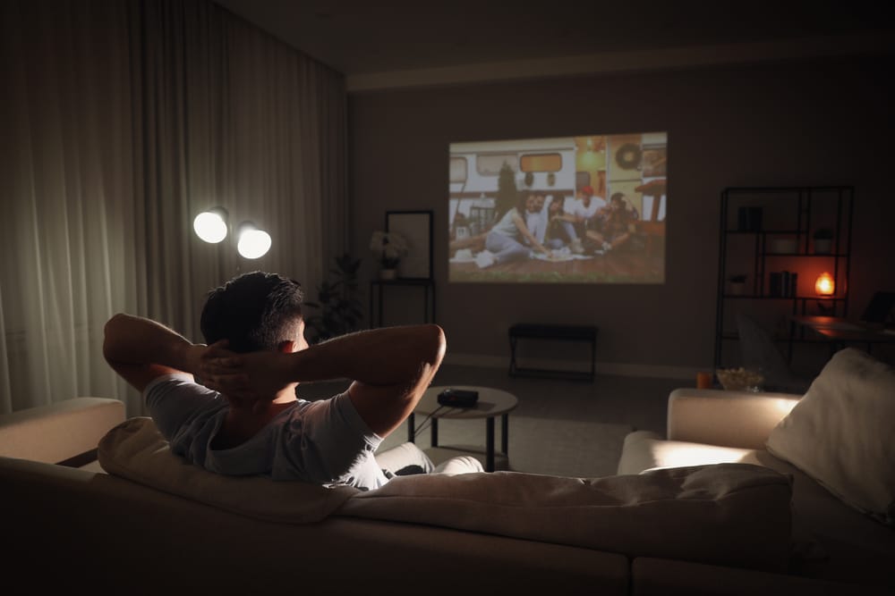 A back view of a person relaxing and watching projector screen