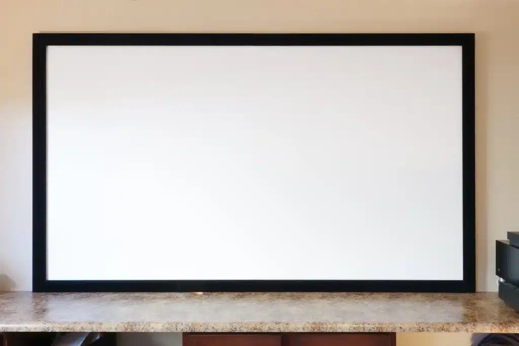 A clean white projector screen framed in black placed on a countertop
