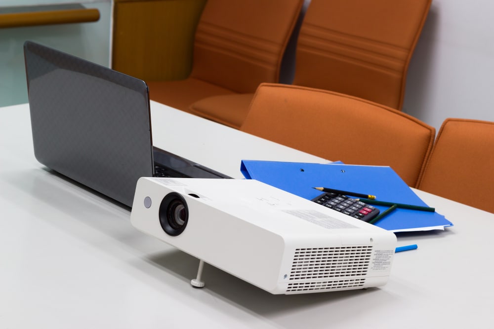 A view of a projector right next to a laptop