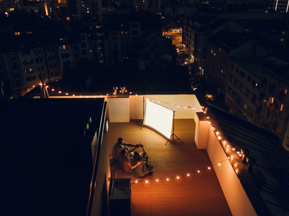 An aerial view of people sitting outdoors looking at a projector with light on