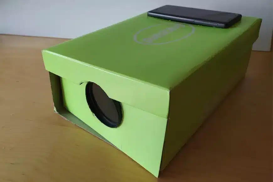 A DIY phone projector made from a cardboard box with a magnifying lens attached