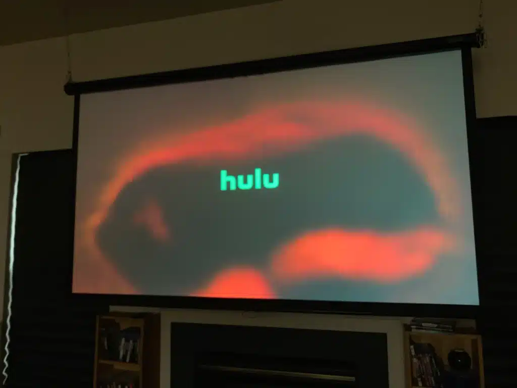 Projector screen displaying a search interface with an on screen keyboard and search suggestions ( )