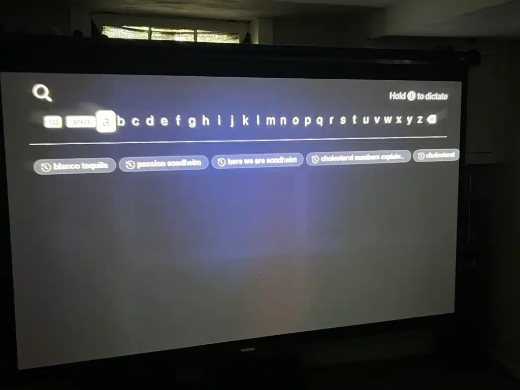 Projector screen displaying a search interface with an on screen keyboard and search suggestions