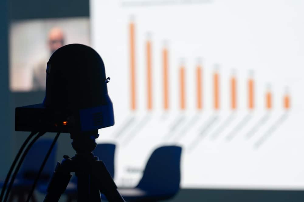 A view of a camera recording a presentation in the background