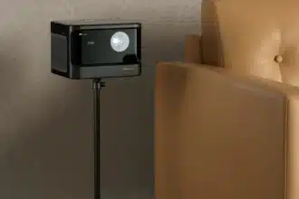 A projector placed on a sleek black floor stand next to a tan leather armchair projecting an image