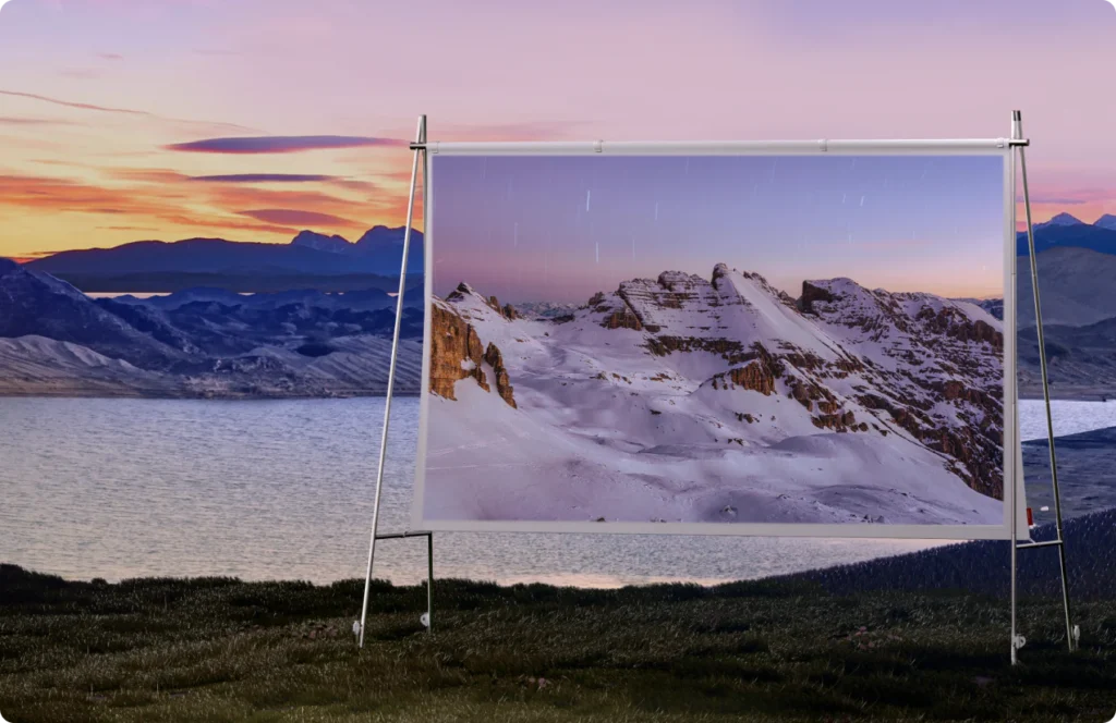 An outdoor projector screen displaying a snowy mountain scene at sunset