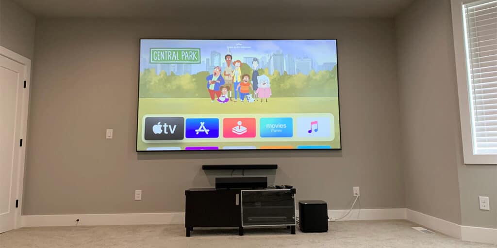 A projector screen displaying a cartoon show in a modern living room setup with a media console